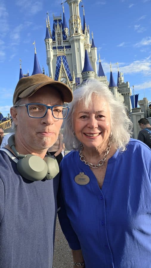Selfie of two visitors in front of Cinderella Castle at Disney World clear blue sky in the background
