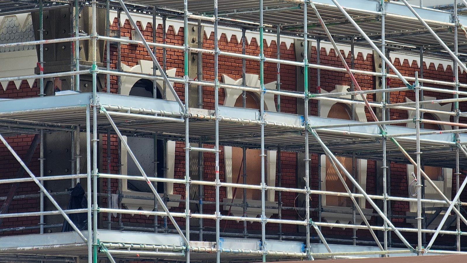Brick building under construction with metal scaffolding surrounding the façade
