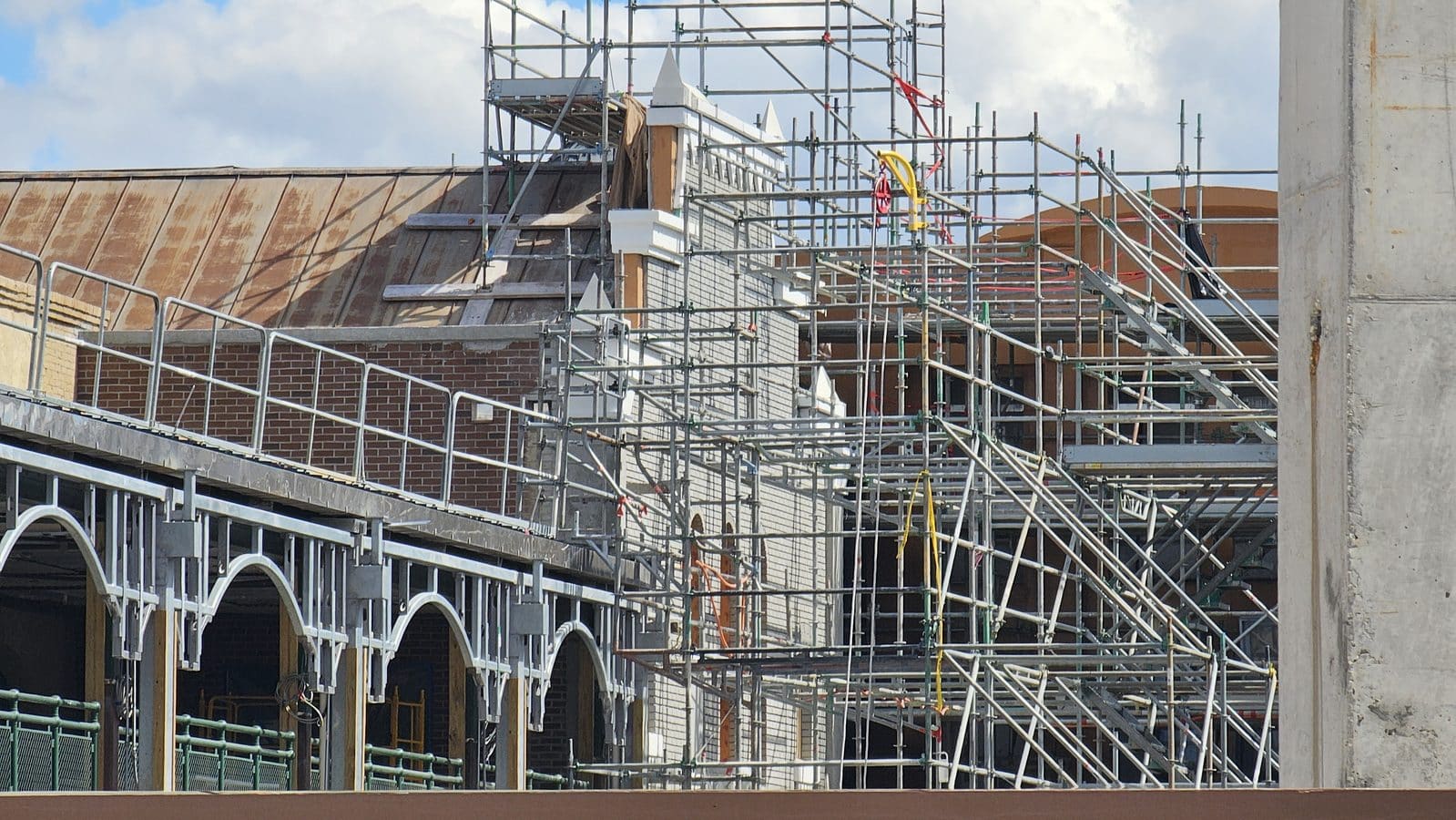 Extensive scaffolding surrounds a brick building under renovation with metal rails and ladders visible