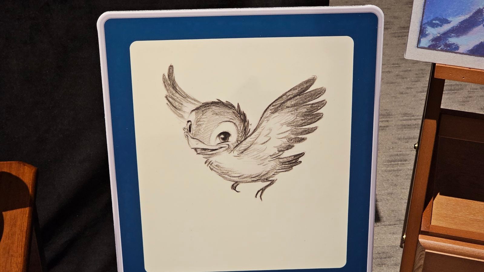 Sketch of a flying cartoonish bird on a light panel inside a blue frame display board