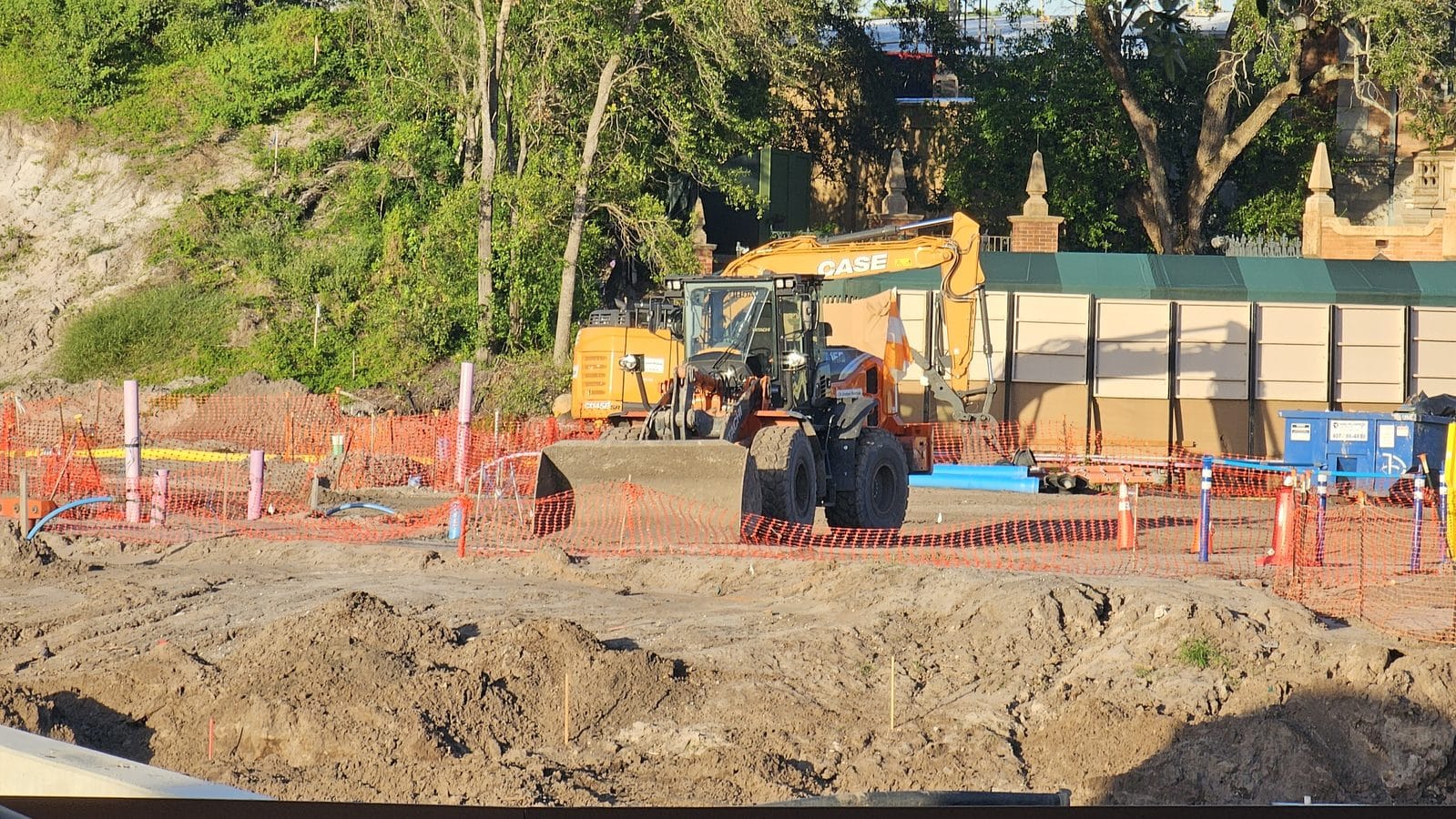Tall concrete walls in front of a white Liberty Square building at the Piston Peak construction site with a Bobcat skid steer