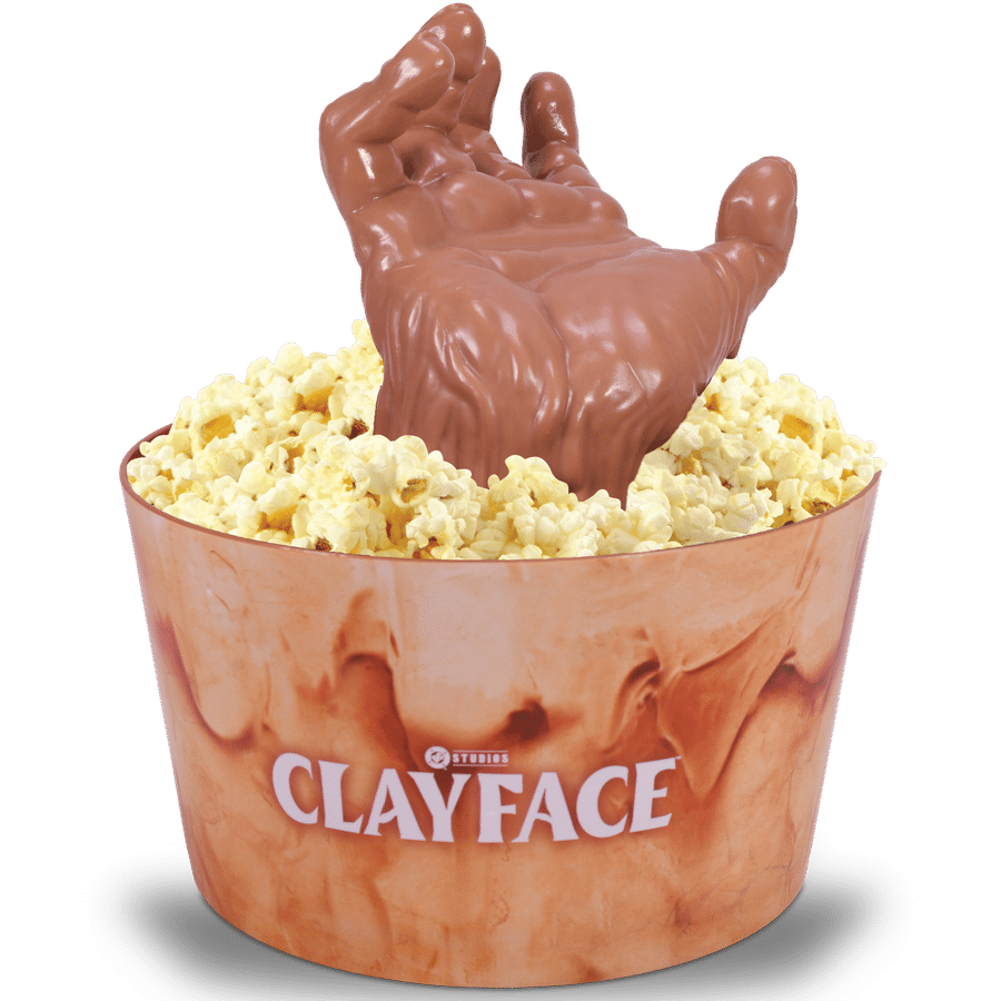 A large chocolate hand emerging from a popcorn filled paper cup like a dessert sculpture