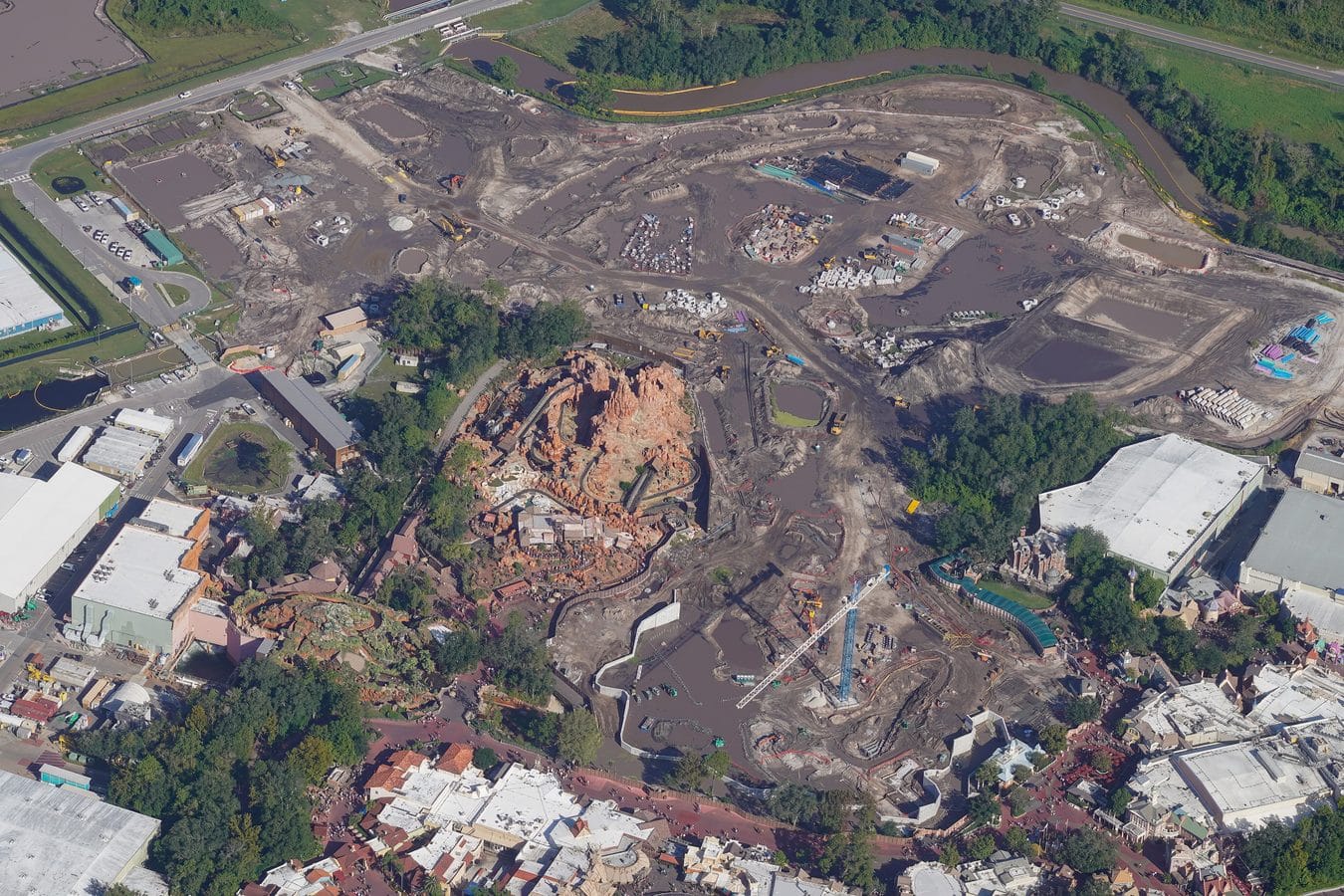 Aerial view of a large construction site with muddy earth excavators piles of materials and surrounding roads
