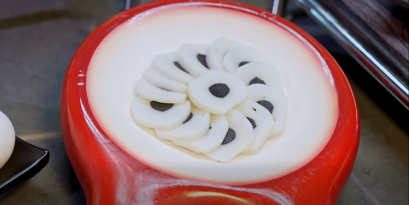 Red stand mixer with white frosting decorated in a flower pattern on top of a cake or surface