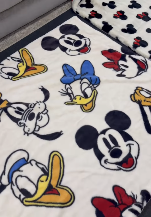 White fleece blanket with large Disney character faces Mickey Mouse Minnie with blue bow Donald Duck and Daisy Duck on a white background