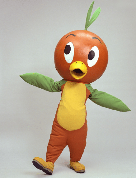 Person in an orange bird mascot costume with green wings and a yellow belly standing with arms outstretched in a playful pose