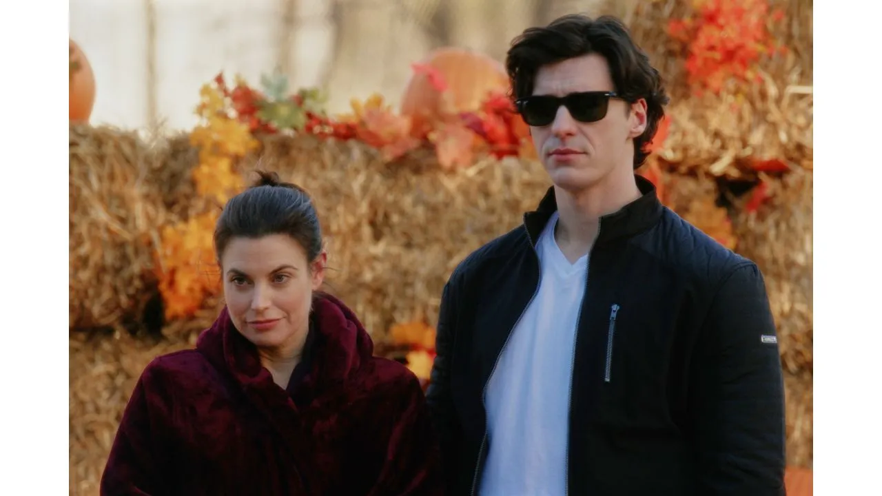 spiritofhalloween4 Fantasy Land News Two adults stand side by side outdoors in autumn a woman in a burgundy coat and a man in a black jacket and sunglasses with hay bales in the background